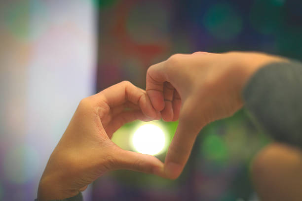 istock Woman making heart shape light bokeh background 534323340