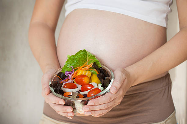istock Pregnant woman's belly and vegetable salad 534325672