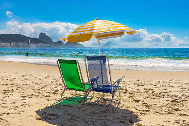 strandkörbe und sonnenschirm am strand der copacabana in rio de janeiro - urca stock-fotos und bilder