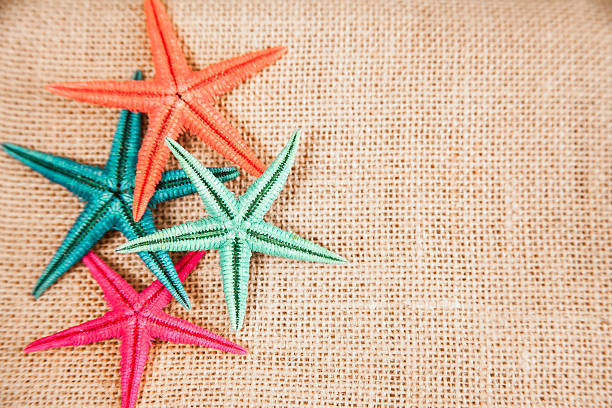istock Summer vacation.  Colorful starfish on burlap background. 534334284