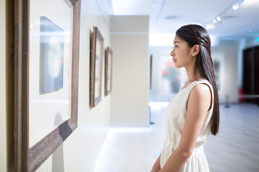 Minimal portrait of teenage boy looking at abstract art on wall in art gallery or museum, copy space