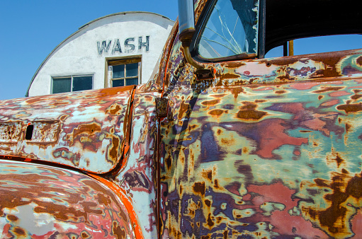 Old rusty truck in front of old quonset style building in the background, Mojave Desert, California.