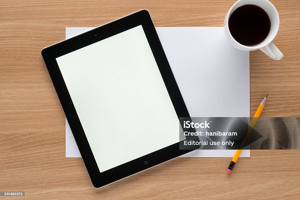 Tablet PC on a worktable Seoul, Korea - November 10, 2014: Apple iPad on a worktable. It has two cameras for FaceTime and HD video recording. The white screen is due to the application. (1-Click Flashlight)  Big Tech Stock Photo