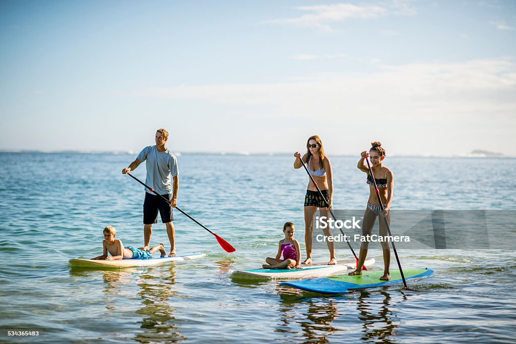 SUP - Stand up paddleboarding family Family in Hawaii's tropical climate enjoying their vacation on stand up paddleboards (SUP) in the sea. Family Stock Photo