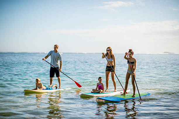 SUP - Stand up paddleboarding family Family in Hawaii's tropical climate enjoying their vacation on stand up paddleboards (SUP) in the sea. paddleboard photos stock pictures, royalty-free photos & images