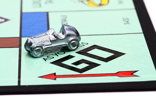 West Palm Beach, USA - April 16, 2014: A partial view of a Monopoly game board showing the Go start square with the Race Car game piece set up on the board. Monopoly is a popular board game that is owned and distributed by Hasbro.