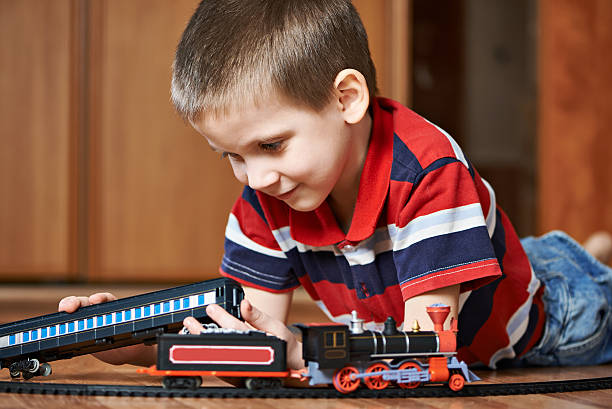 istock Little boy playing with railway lying on floor 534367025
