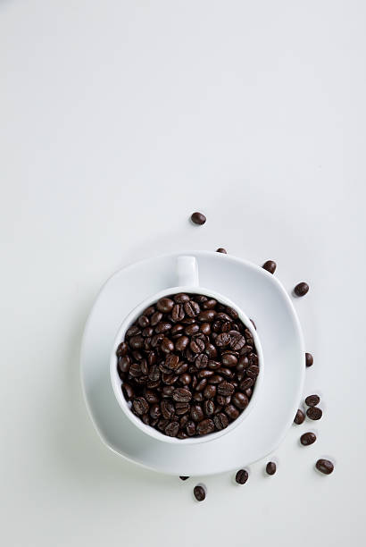Filiżanka kawy i ziarna na białym tle. – zdjęcie