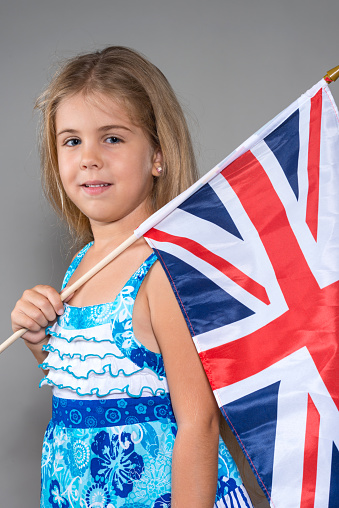 Little girl holding a british flag on gray background