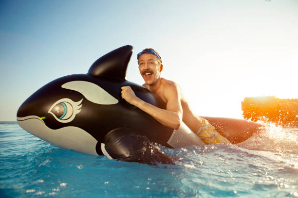 hombre jugando en una ballena inflated - floatation device fotografías e imágenes de stock