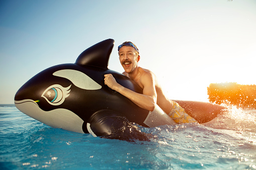 Man playing on a inflated whale. Generic produced inflatable, there already images accepted with this product. 