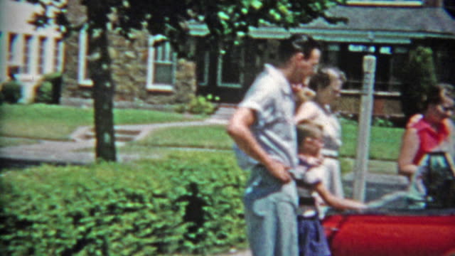 1953: Family checking out new red 53' Chevy car packing up and driving away.