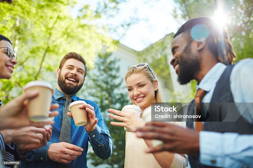 Outdoor refreshment Joyful business team with coffee interacting in park Outdoors Stock Photo