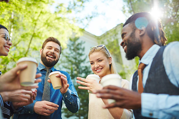 Outdoor refreshment Joyful business team with coffee interacting in park colleagues outside stock pictures, royalty-free photos & images