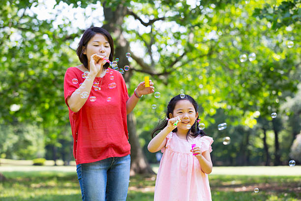 istock Little girl and mother blowing bubbles 534402604