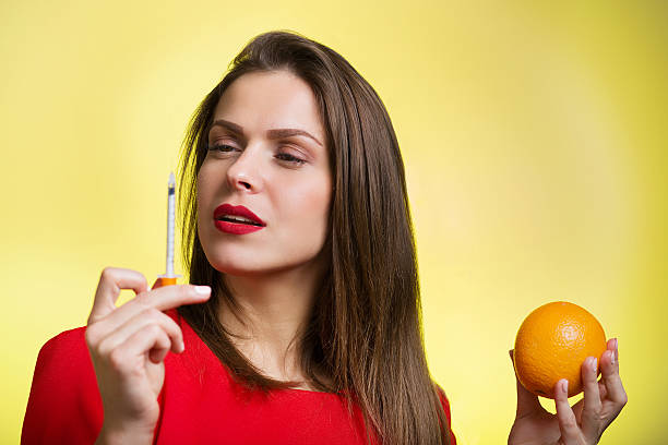 donna che tiene una siringa e arancio - human lips orange lipstick human mouth foto e immagini stock