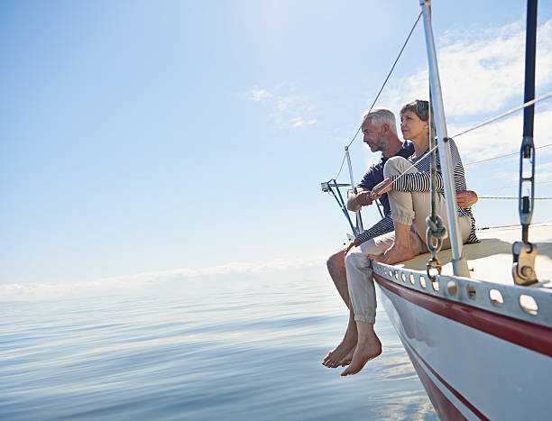 Taking in the view Shot of a loving mature couple on a sailboat looking out onto the ocean sailing couple stock pictures, royalty-free photos & images