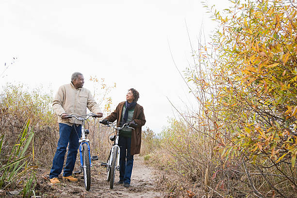 o casal empurrando bicicletas - couple senior adult travel action - fotografias e filmes do acervo