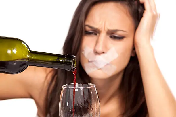 Photo of Girl with sticky tape over her mouth pours wine