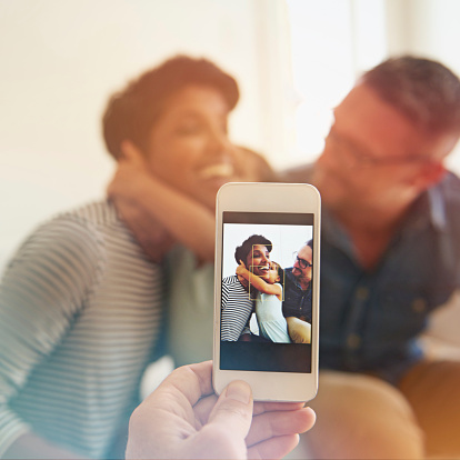 Cropped shot of someone taking a photo of a family of three on a camera phone