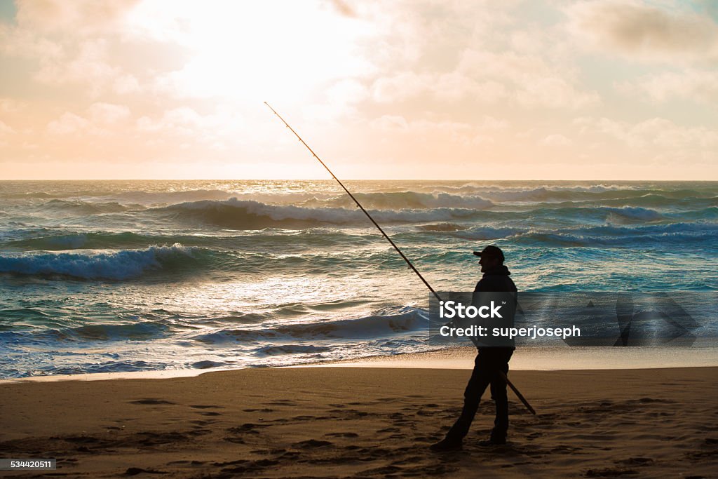 Man fishing on Beach at Sunset Cultures Stock Photo