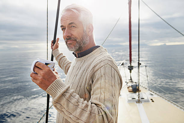 The sweet life on deck Shot of a mature man on his sailboat drinking a cup of coffee rich man stock pictures, royalty-free photos & images