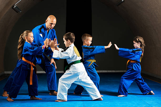 Karate training. Mid adult instructor practicing martial arts with group of children.    judo photos stock pictures, royalty-free photos & images