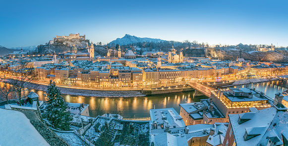 Beautiful detailed Panorama of Salzburg with the famous Hohensalzburg Festung covered in fresh Snow at sunset with the street lights just gone on. The most famous town in Austria where Mozart was born.
