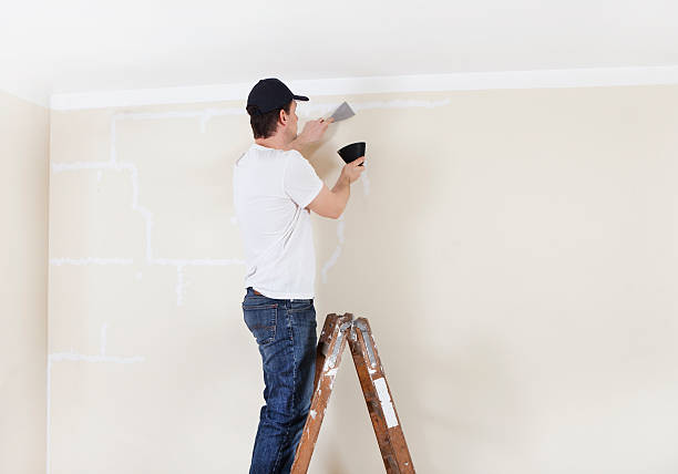 istock Man on ladder spackles wall 534426641