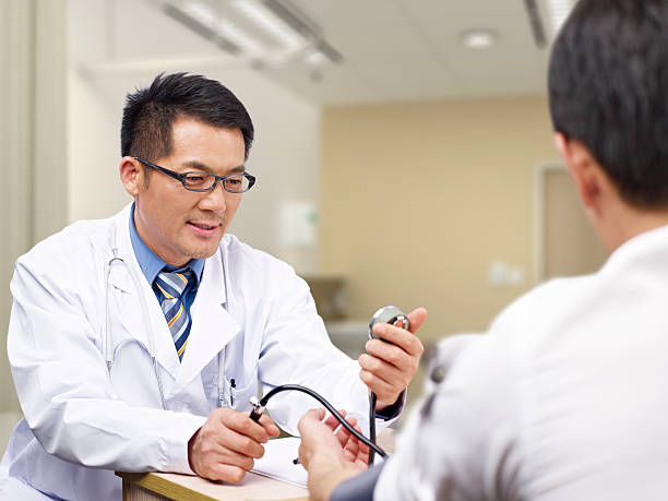 азиатские доктор и пациент - patient blood pressure gauge doctor male стоковые фото и изображения