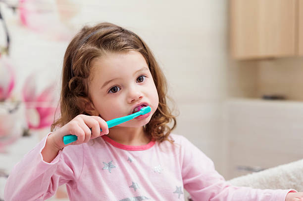 piccola bambina in pigiama rosa in bagno, lavarsi i denti - healthy lifestyle human teeth adult brushing foto e immagini stock