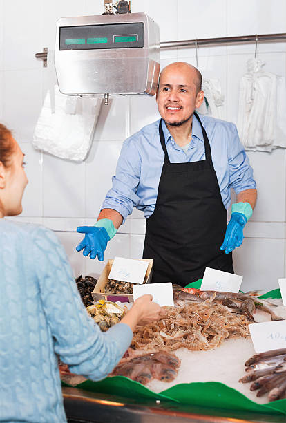 istock Mature seller helping female customer to choose  fish 534452930