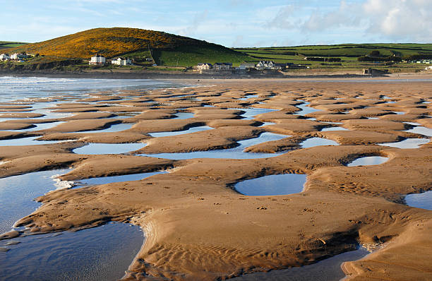 Tidal Pools on a Sandy Beach in Devon A receding tide at Croyde Bay leaves pools of sea water behind on a Devon, UK, beach during high summer.  croyde photos stock pictures, royalty-free photos & images