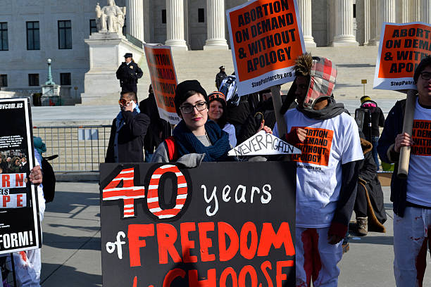 Young Woman Protesting At U.S. Sumpreme Court Washington D.C., USA - January 22, 2015; A Young woman holds a pro-choice sign at the U.S. Supreme Court in Washington D.C. abortion photos stock pictures, royalty-free photos & images