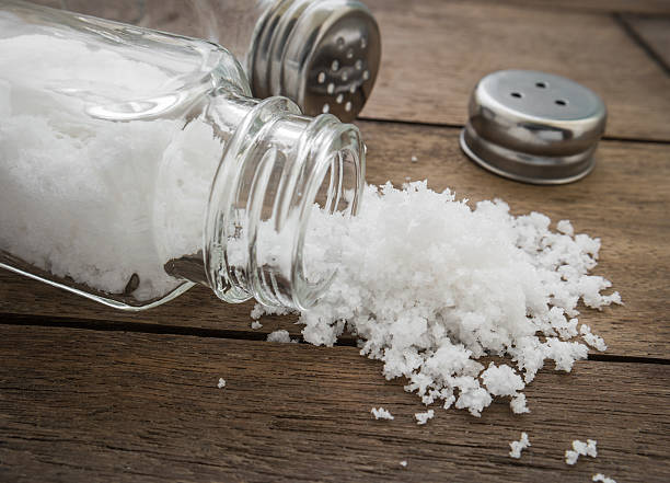 istock Spilled salt with salt shaker on wooden background 534472827