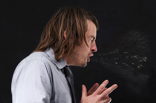 Profile view of a young businessman sneezing