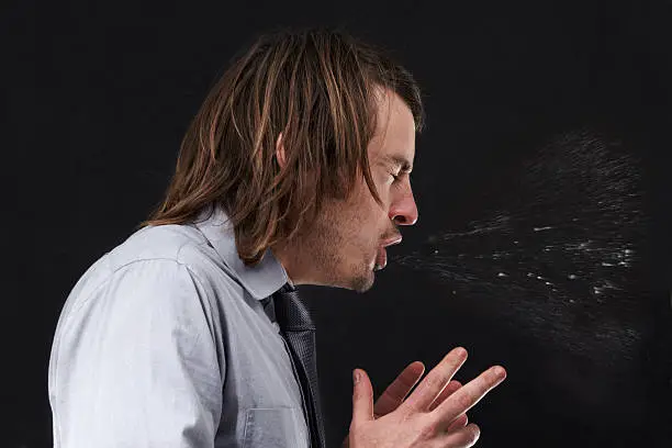 Profile view of a young businessman sneezing