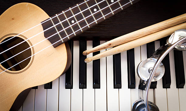 Music instruments. Music instruments. Ukulele, drum sticks, tambourine on piano. Top view with dark vignette. acoustic music photos stock pictures, royalty-free photos & images