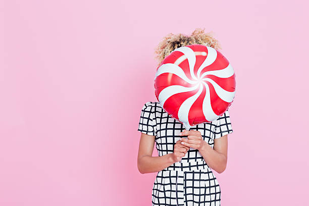Young woman holding candy shaped balloon