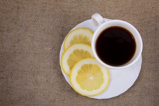Cup of coffee with fresh lemon on the natural burlap