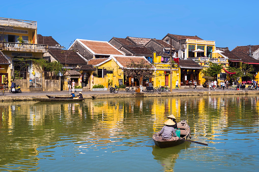 Hoi An, Vietnam - January 27, 2014: View of old shophouses at UNESCO-listed Hoi An Ancient Town and boats on the Thu Bon river in Hoi An, Central Vietnam.