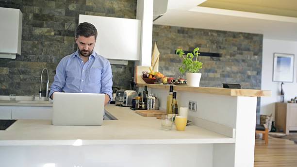 istock Man at kitchen countertop working on laptop from home 534495070
