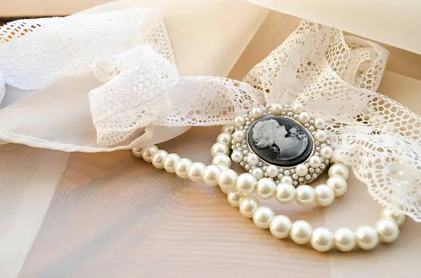 vintage cameo, pearls and lace on beige background