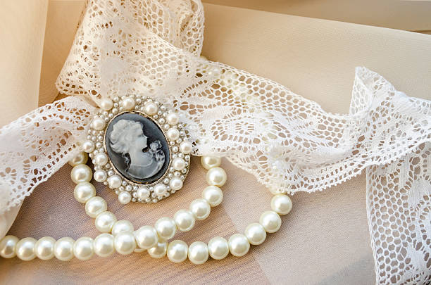 vintage cameo, pearls and lace on beige background
