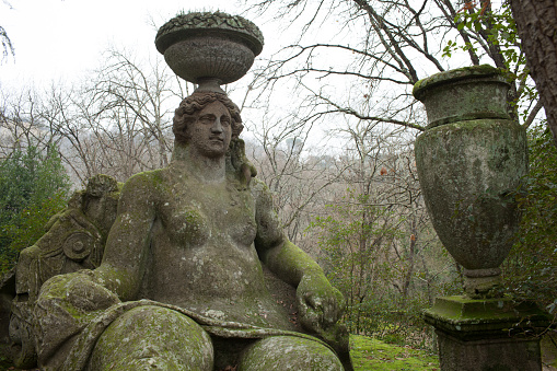 Bomarzo, Italy - January 10, 2015: Moss-covered statue of goddess Ceres with a basket on her head, filled with grain and fruit, which normally are his attributes. Park Of The Monsters, Bomarzo, Lazio, Italy.