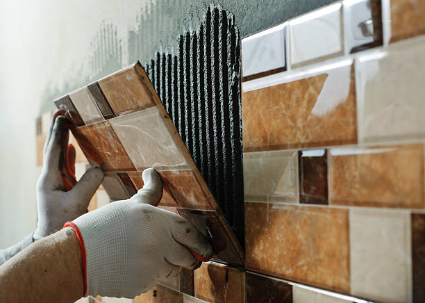 Laying Ceramic Tiles. Laying Ceramic Tiles. Tiler placing ceramic wall tile in position over adhesive tile stock pictures, royalty-free photos & images