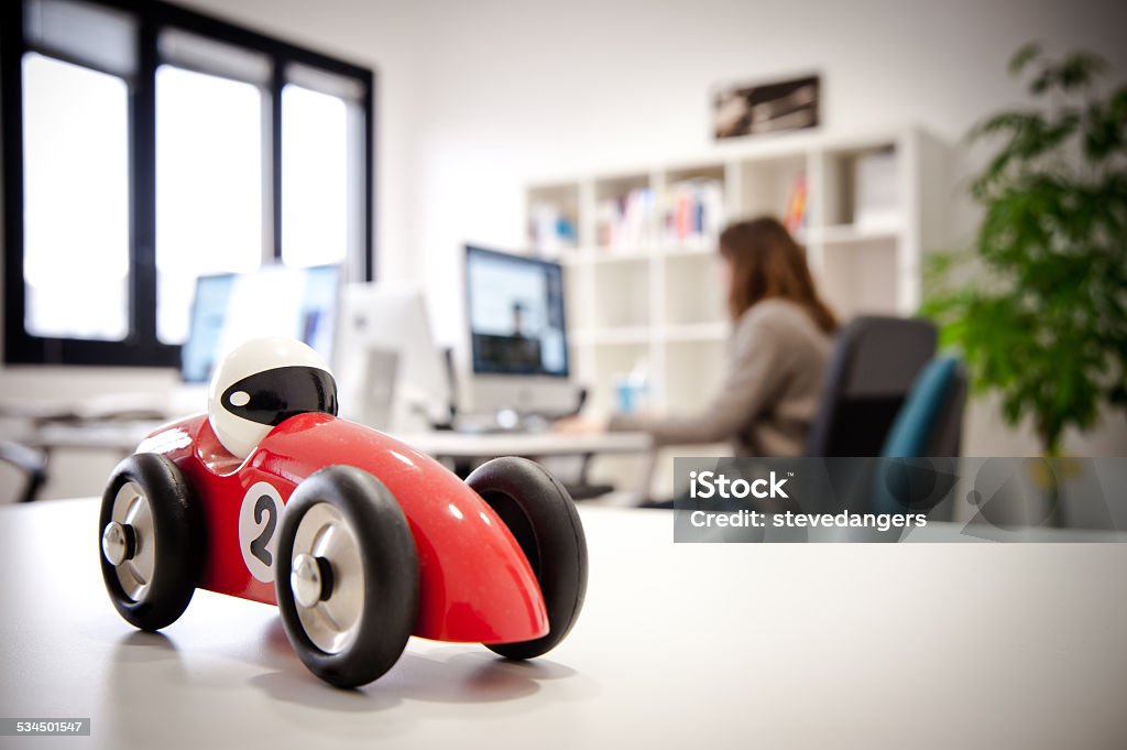 Race car Model on a Office desk A shoot inside an Office with a defocused Girl at computer  in background, focus on foreground on a race car model on a desk. Manager Stock Photo