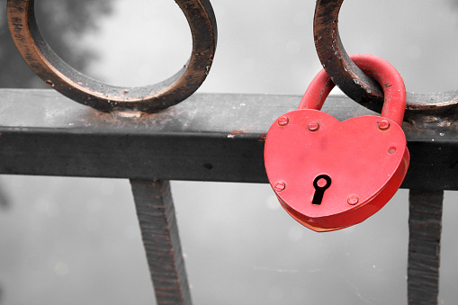 Lock in heart shape on the railing of bridge - a symbol of happy and long married life of bride and groom. Conceptual photo.