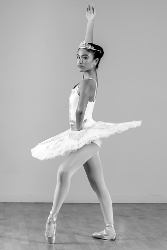 Young ballerina practicing dance moves on black background