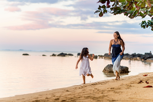 Mother and daughter playing together on the beach in the tropical climate of Kauai, Hawaii